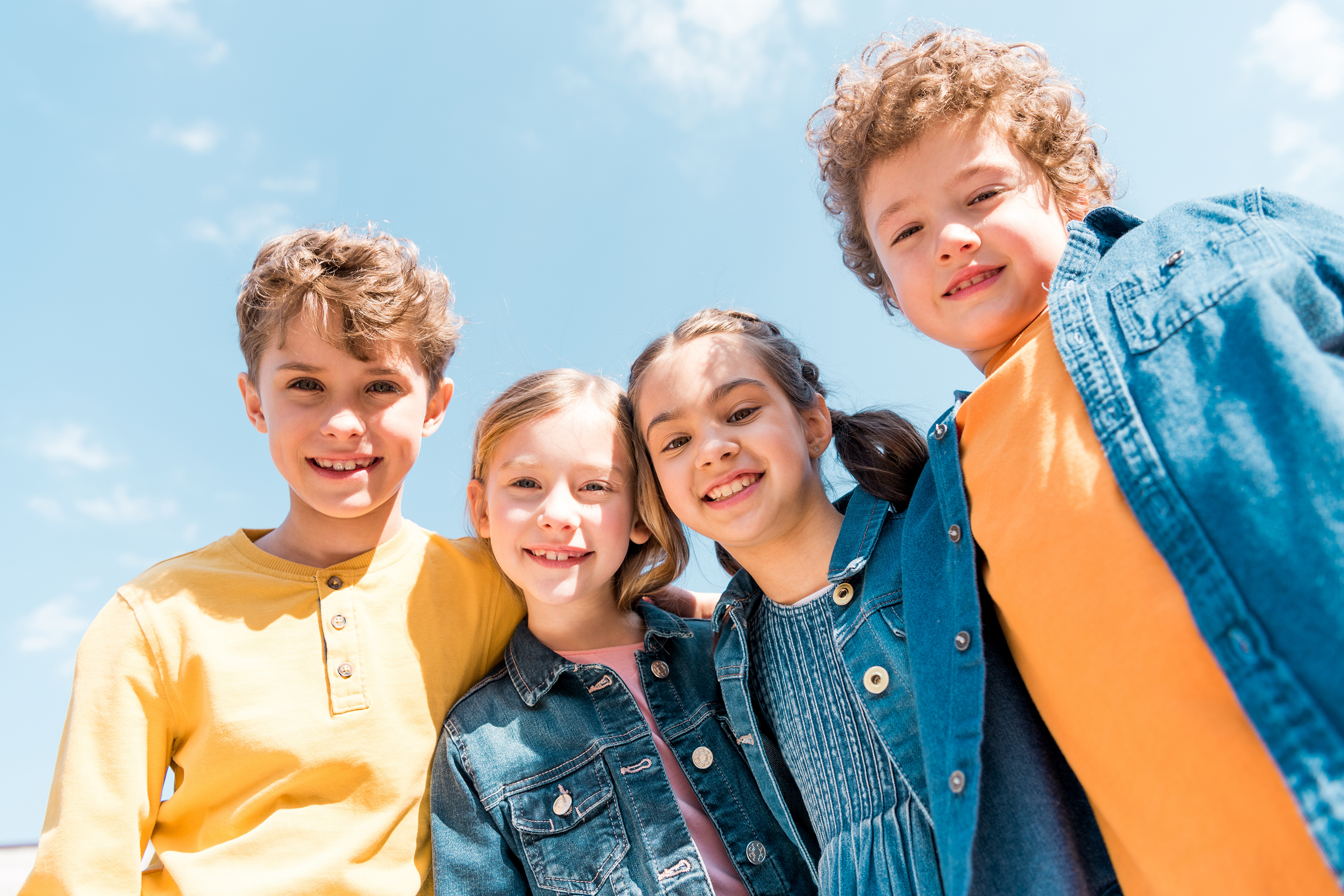 Four kids in denim jackets smiling